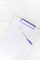 Free photo pen over white paper on clipboard against white background