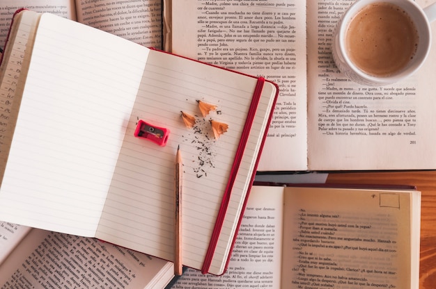 Pencil and notebook near coffee and books