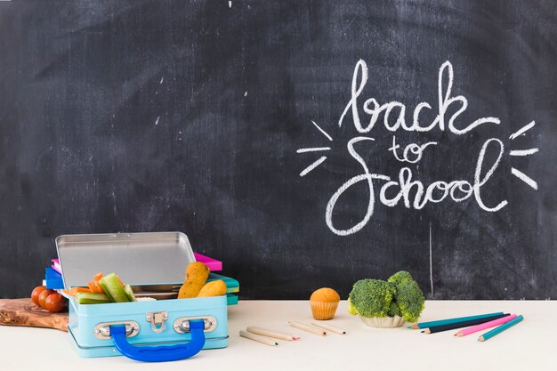 Pencils and lunchbox near blackboard