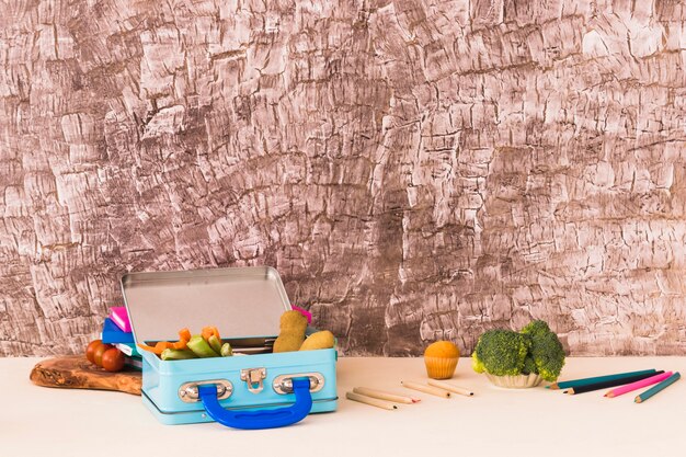 Pencils and lunchbox near textured wall
