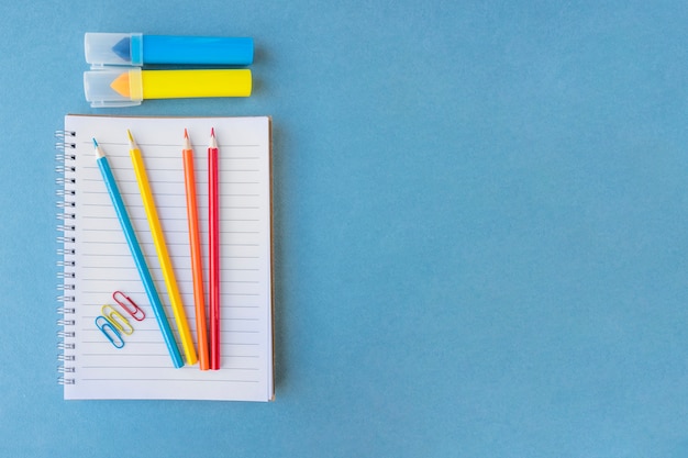 Pencils and markers near notebook and clips