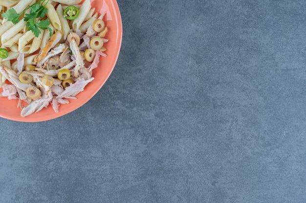 Penne pasta with chicken on orange plate. 