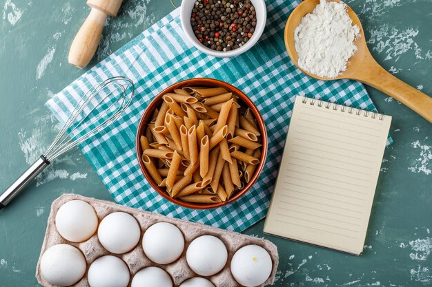 Penne pasta with eggs, peppercorns, starch, whisk, rolling pin and copybook