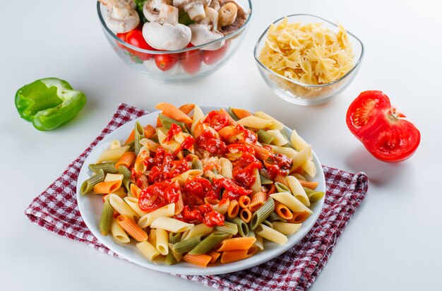 Penne pasta with mushroom, tomato, sauce, pepper, raw pasta in a plate