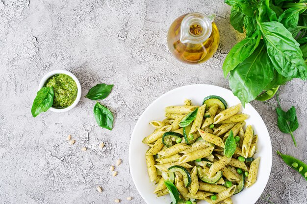 Penne pasta with  pesto sauce, zucchini, green peas and basil. Italian food. Top view. Flat lay.