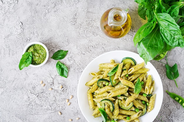 Penne pasta with  pesto sauce, zucchini, green peas and basil. Italian food. Top view. Flat lay.