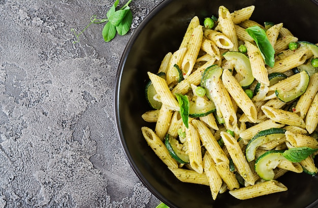 Penne pasta with  pesto sauce, zucchini, green peas and basil. Italian food. Top view. Flat lay.