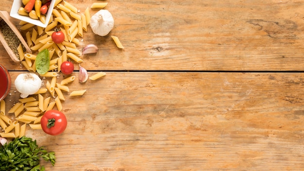 Penne pasta with vegetables ingredients on old wooden table