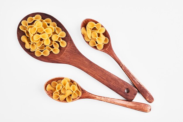 Penne pasta in wooden spoons.