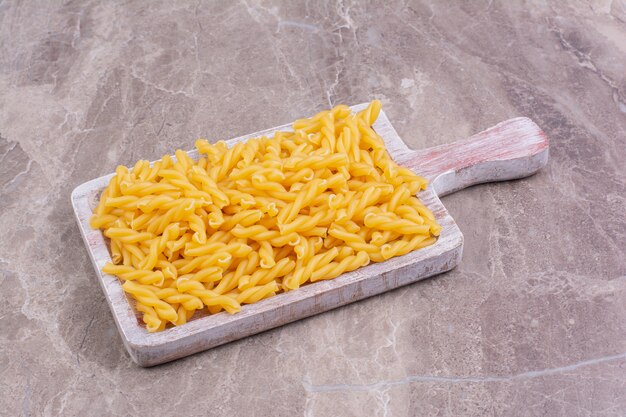Penne pastas on a blue rustic wooden platter. 