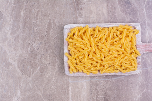 Pasta di penne su un piatto di legno rustico blu.