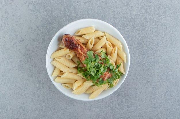 Penne with roasted chicken in white bowl.