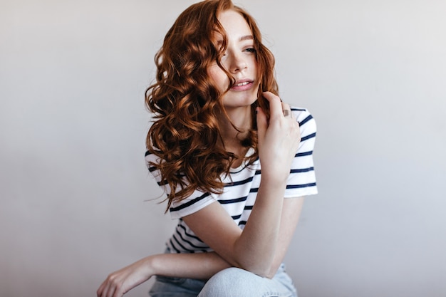 Free photo pensive adorable woman in striped t-shirt looking away. indoor photo of glamorous ginger lady.