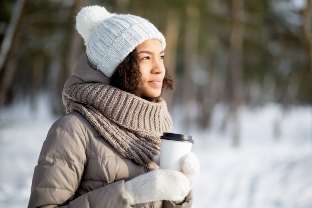 冬の森を歩いている幸せなアフリカの女性