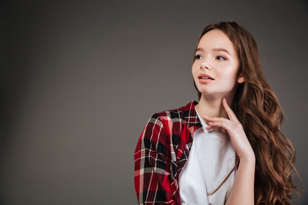 Pensive attractive woman in plaid shirt standing and looking away