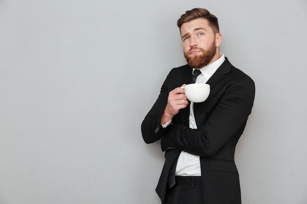 Foto gratuita pensoso uomo barbuto in possesso di una tazza di caffè