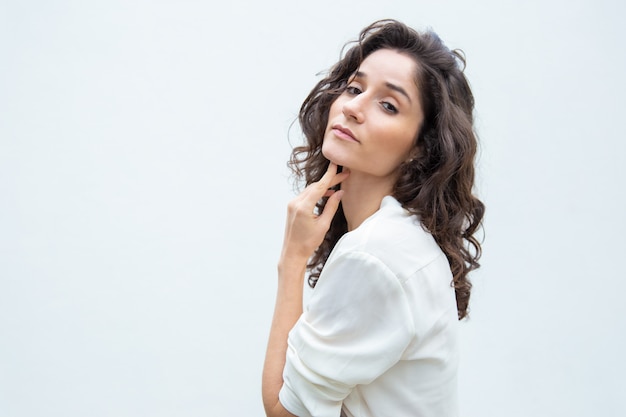 Pensive beautiful woman touching chin and neck skin