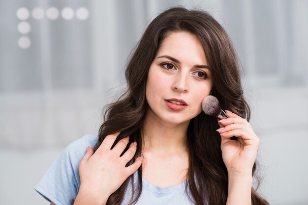 Pensive beautiful woman with makeup brush