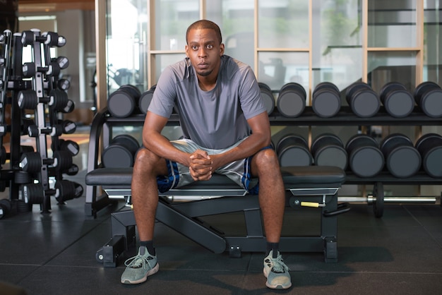 Uomo di colore pensieroso rilassante in palestra e guardando lontano