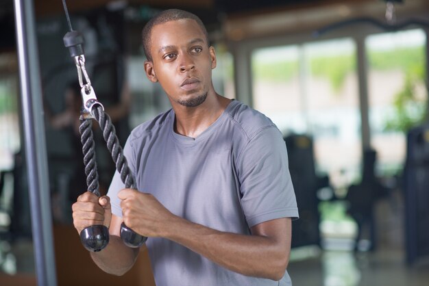 Pensive black man using gym equipment and looking away