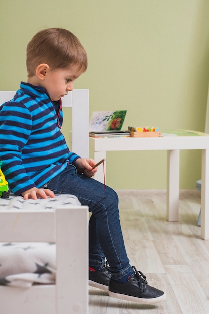 Free photo pensive boy sitting on bed