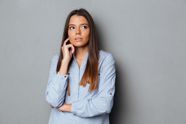 シャツがよそ見で物思いにふけるブルネットの女性