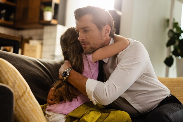 Pensive business father embracing is daughter before going to work