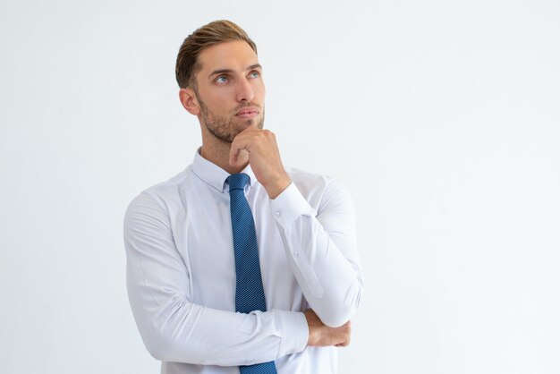 Pensive business man touching chin and looking away