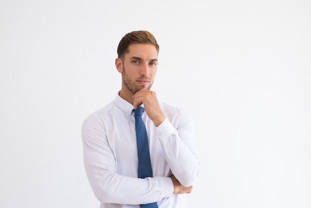 Pensive business man touching chin and looking at camera