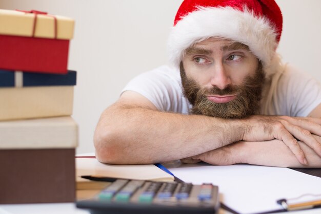 Pensive business man wearing Santa hat and relaxing