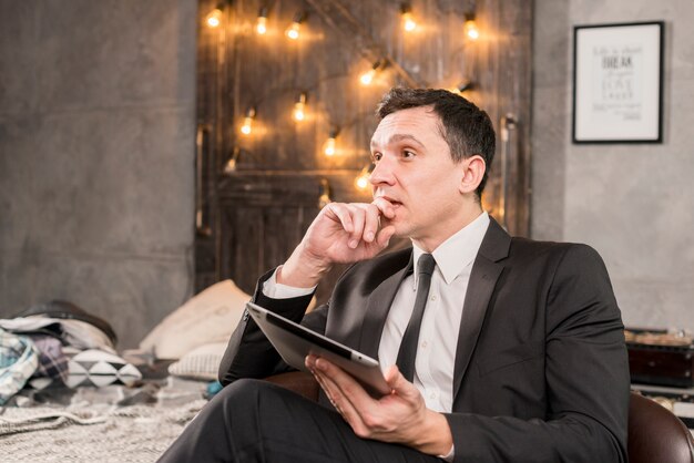 Pensive businessman holding tablet 