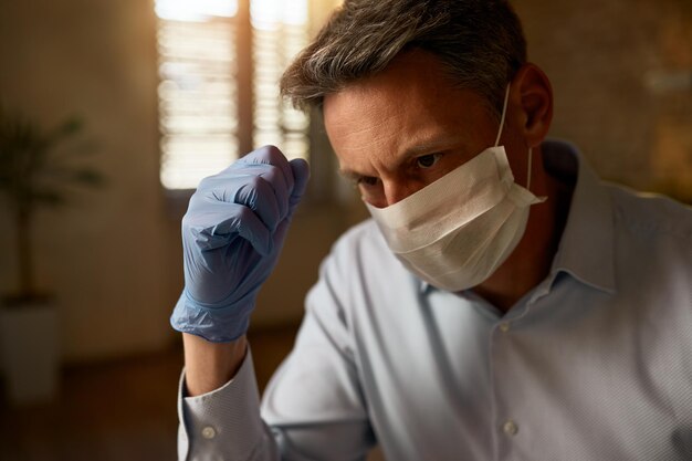 Задумчивый бизнесмен в маске во время работы в офисе во время пандемии COVID19