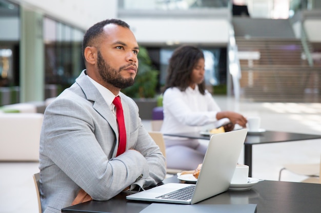 Pensive businessman with laptop thinking over startup strategy