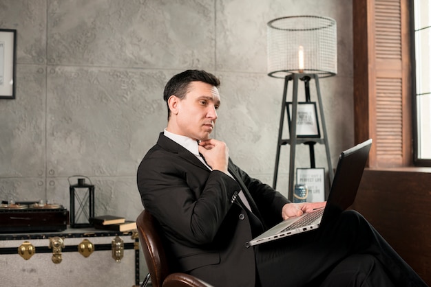 Free photo pensive businessman with laptop working at home