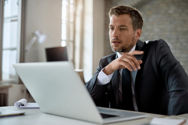 Foto gratuita uomo d'affari pensieroso che lavora in ufficio e legge un'e-mail sul laptop