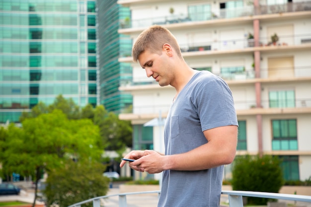 Pensive Caucasian guy using smartphone in urban settings