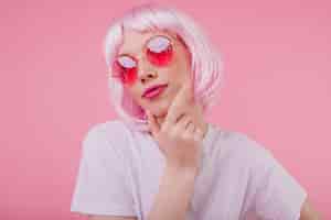 Free photo pensive charming girl with pink hair looking up while posing on pastel background carefree european woman in sunglasses and periwig chilling during studio photoshoot