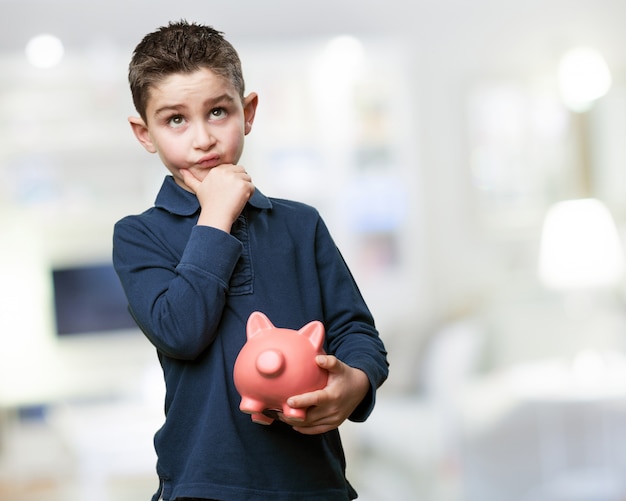 Free photo pensive child with a piggy bank
