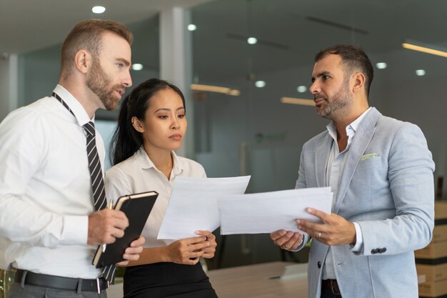 Pensive colleagues viewing business papers in office