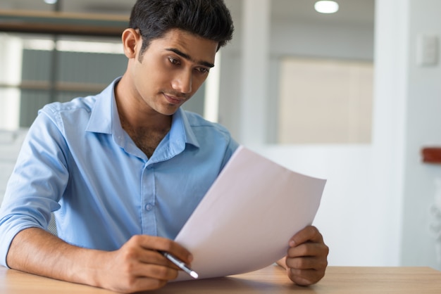 Pensive concentrated Indian lawyer examining paper