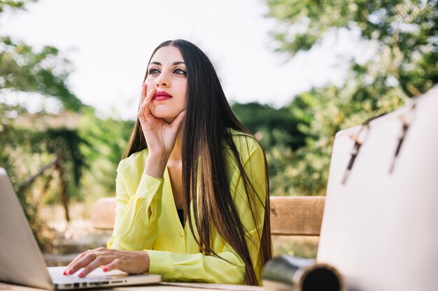 Pensive elegant working in park with gadget