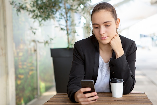 Pensive female office worker testing new mobile app