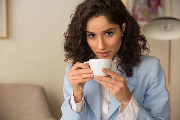 Pensive female professional drinking coffee at home