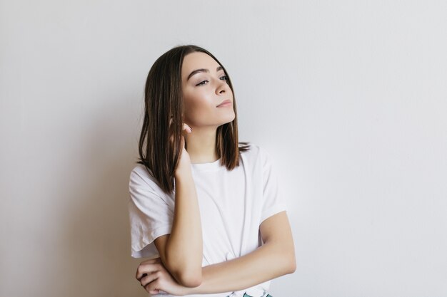 Pensive girl in white t-shirt looking away. Portrait of beautiful caucasian woman isolated.