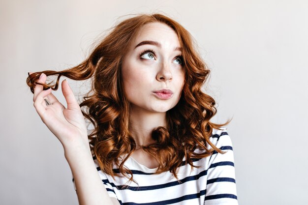 Pensive girl with beautiful ginger hair posing. enchanting stylish woman with curly hairstyle.