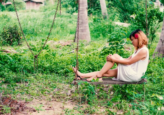 Pensive girl with dress on the swing