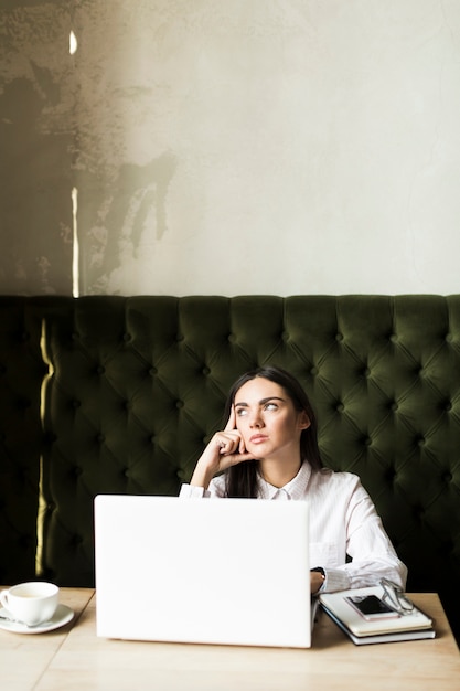 Pensive girl with laptop in cafe