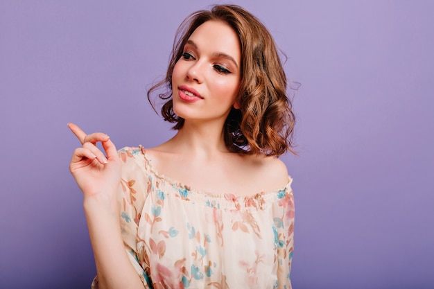 Pensive girl with trendy makeup looking away standing on purple background