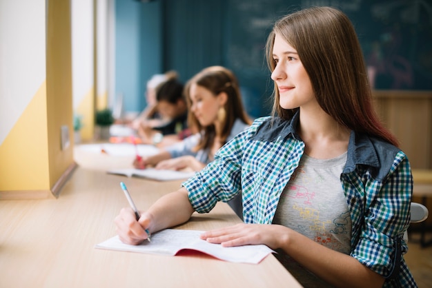 Scrittura pensierosa ragazza e guardando lontano