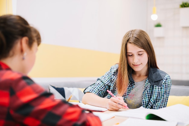 Ragazze pensose scrivere alla scrivania